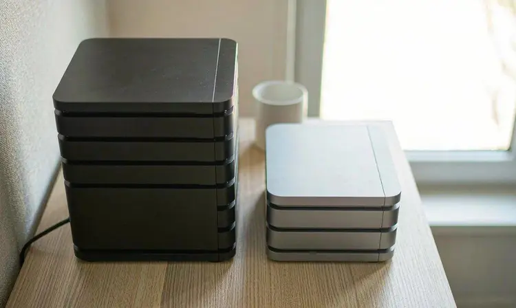 浅色木桌上并排摆放的两台不同形态家用 NAS 主机